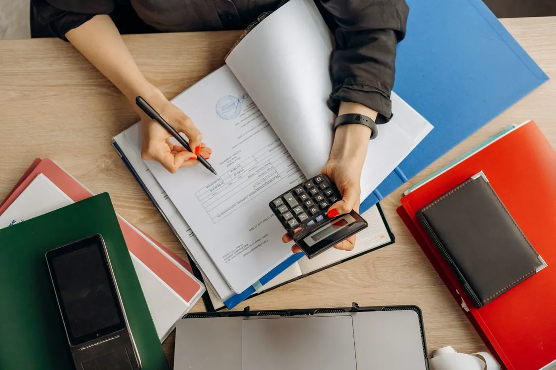 Vérification de pièces comptables avec une calculatrice sur un bureau.