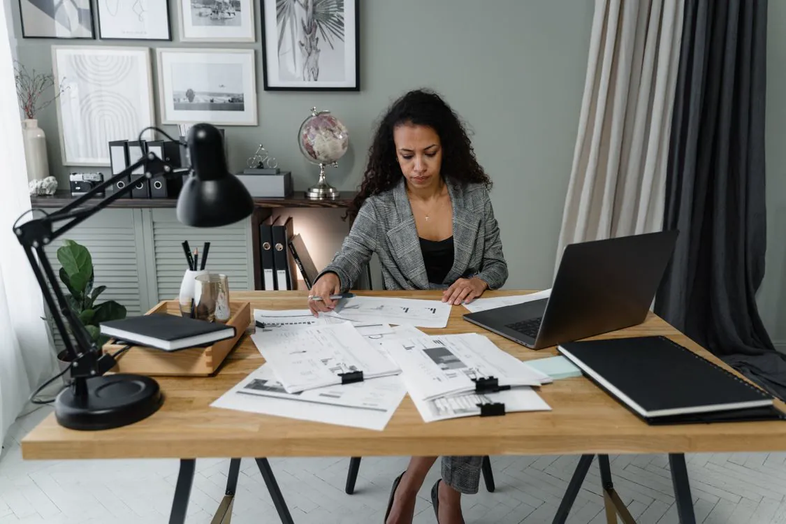 Professionnelle examinant des dossiers sur son bureau à côté d’un ordinateur.
