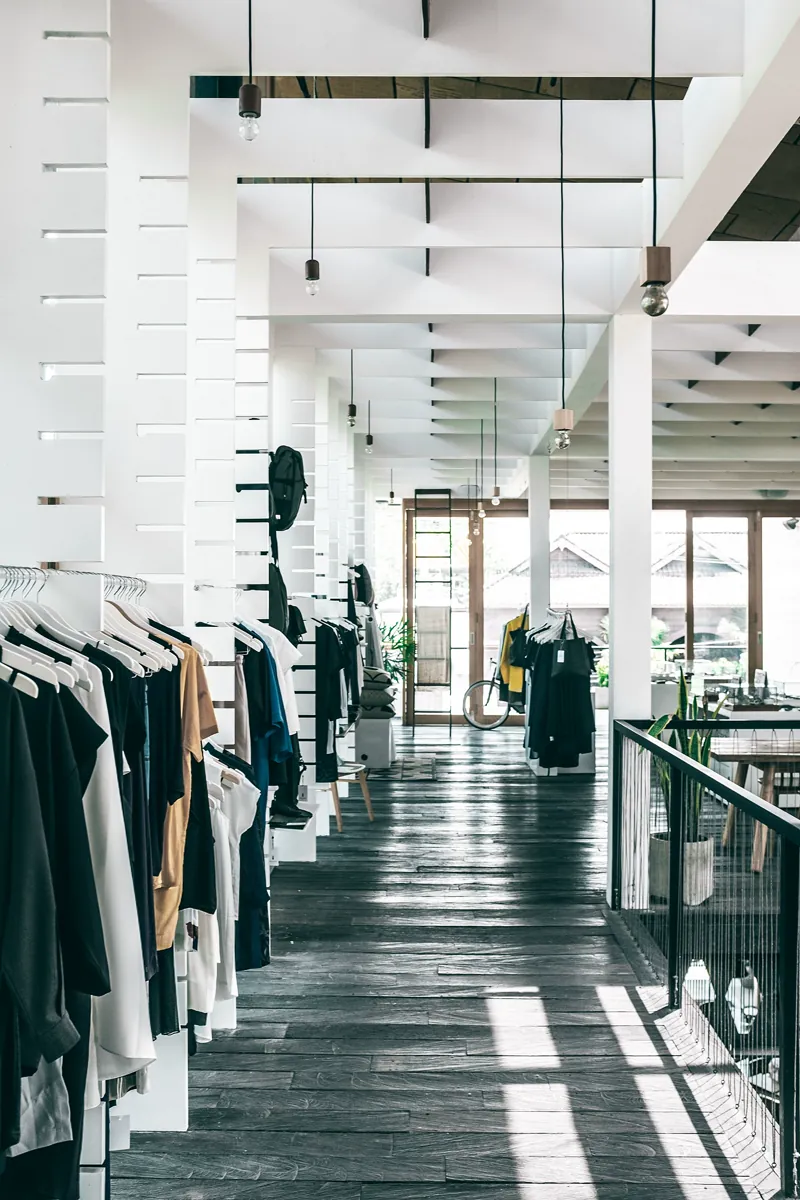 Intérieur d’une boutique avec portants de vêtements et espace de circulation.