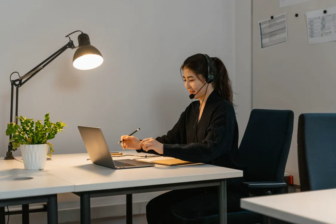 Professionnelle équipée d’un casque, travaillant sur ordinateur pendant un échange à distance.