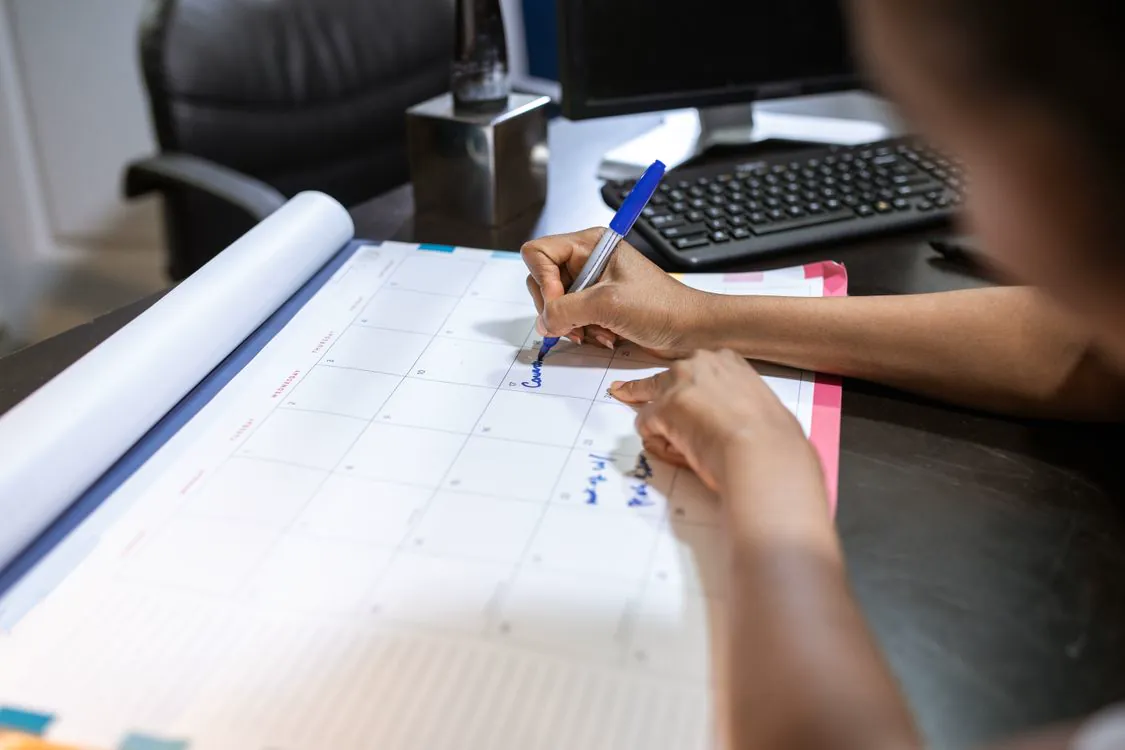 Personne organisant des rendez-vous sur un calendrier de bureau.