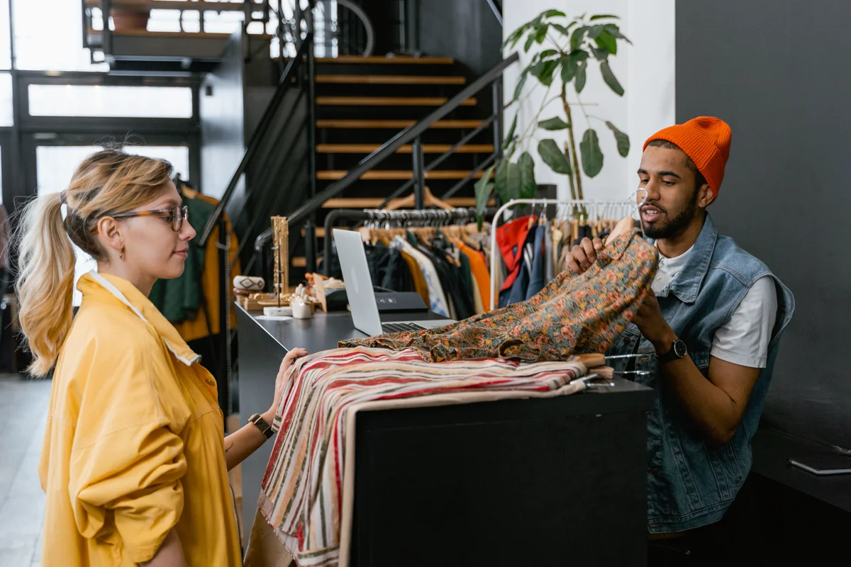 Un vendeur présente un vêtement à une cliente dans une boutique.